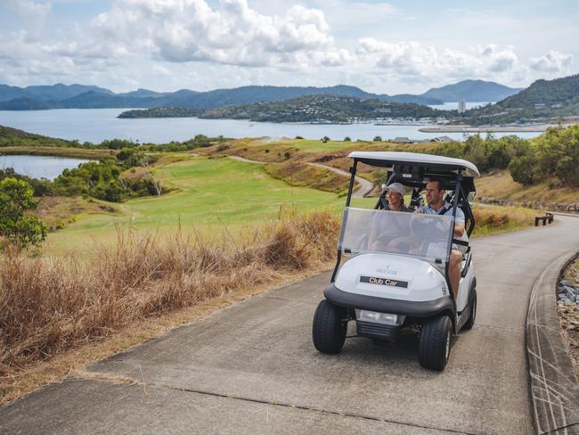 Couple driving the golf buggy towards Hamilton Island Golf Club, located on Dent Island. Hamilton Island golf coursePhoto credit  - Reuben Nutt/Tourism and Events QueenslandESCAPE 25 SeptWhitsundays