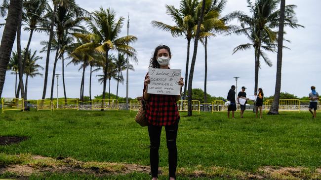 A protester hold a sign as she participates in a ‘Freedom Rally’ protest in support of opening the US state of Florida. Picture: AFP