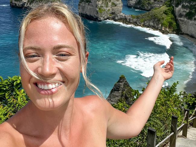 Young female tourist taking selfie at the Manta Bay or Kelingking Beach on Nusa Penida Island, Bali, Indonesia