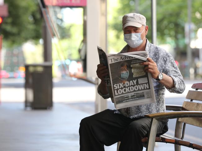A man read’s the Thursday edition of The Advertiser in a deserted CBD on Thursday. Photo: Tait Schmaal.