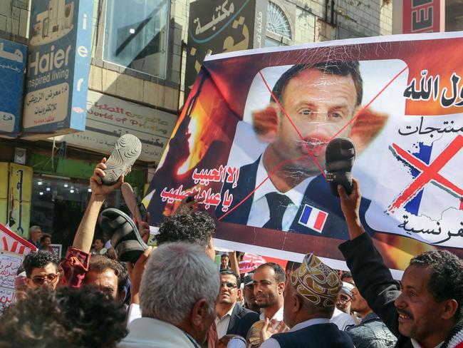 Demonstrators lift slippers against a banner depicting Macron as a pig, during a rally protesting his comments over Prophet Mohammed cartoons, in Yemen. Picture: AFP