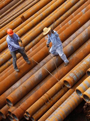 Workers arrange steel pipes at a factory in Huaibei.