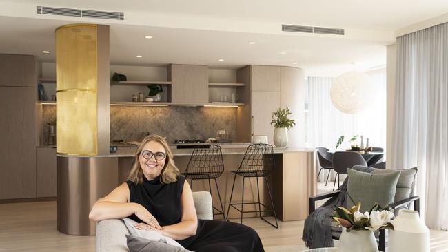 Interior designer Alexandra Kidd in the living room of her Potts Point apartmen with her stunning gold kitchen in the background. Picture: Matthew Vasilescu