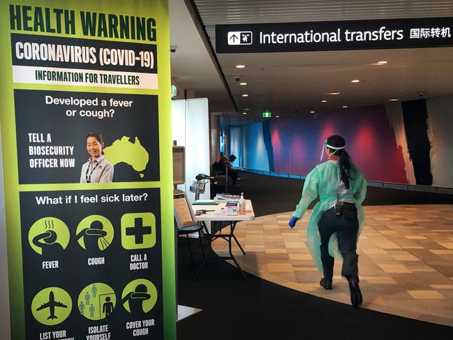 A staff member in protective medical clothing moves through the arrivals area at Brisbane International Airport. (Photo by Lisa Maree Williams/Getty Images)