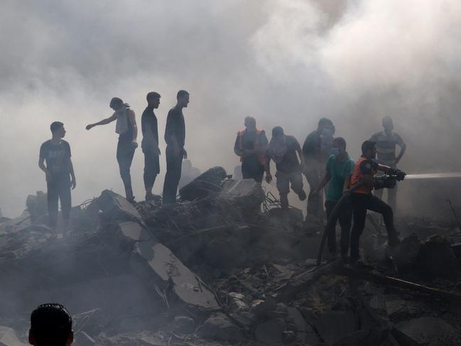 EDITORS NOTE: Graphic content / Palestinians stand on the rubble of a building as a civil defence worker uses a water hose following an Israeli strike in the southern Gaza Strip, as battles between Israel and the Hamas movement continue for the sixth consecutive day on October 12, 2023. Thousands of people, both Israeli and Palestinians have died since October 7, 2023, after Palestinian Hamas militants entered Israel in a surprise attack leading Israel to declare war on Hamas in the Gaza Strip enclave on October 8. (Photo by SAID KHATIB / AFP)