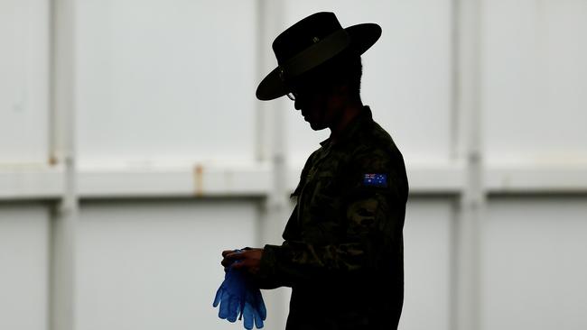 A member of the Defence Force puts on protective gloves at Sydney Airport.