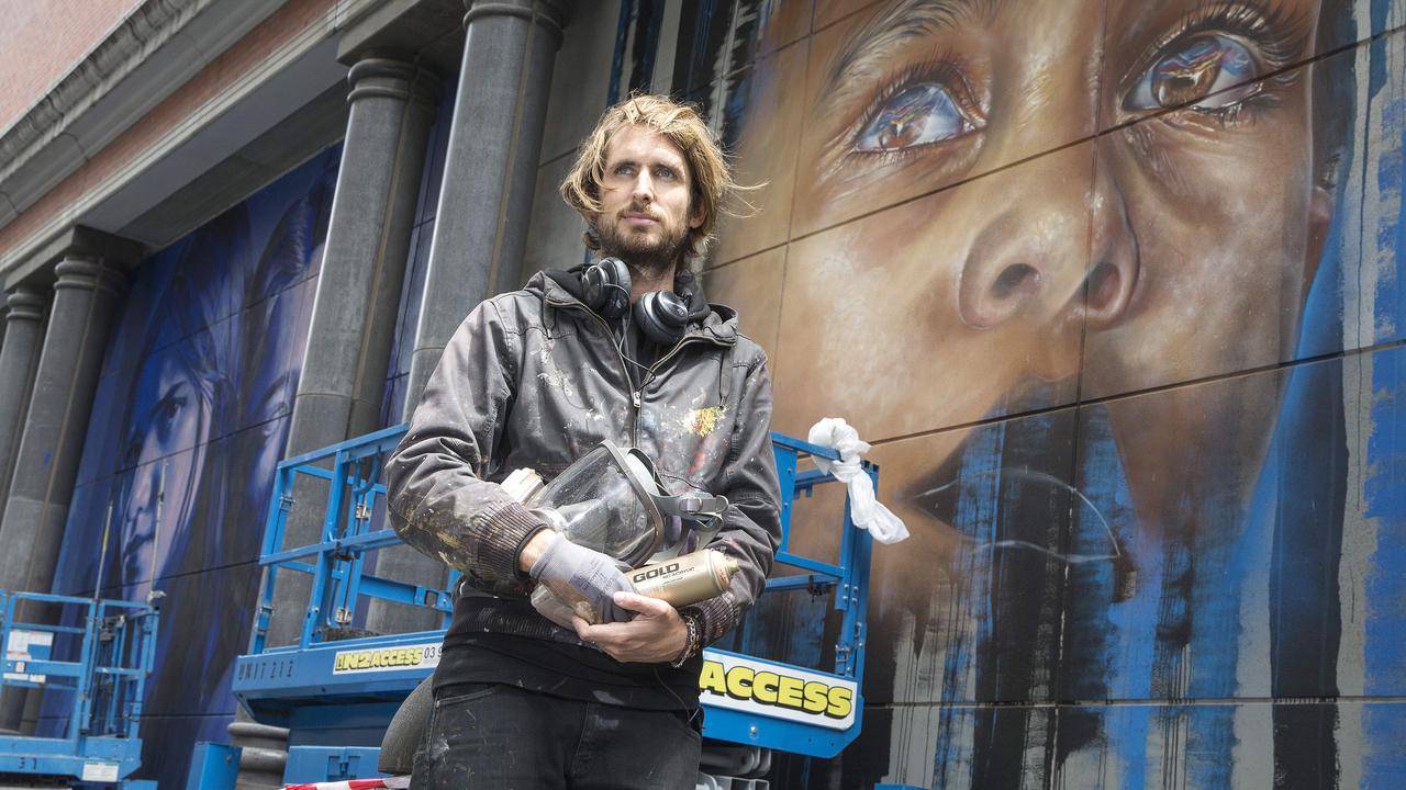 Artist Matt Adnate in front of his portrait of a young Indigenous boy on Spencer St. Picture: Michael Klein