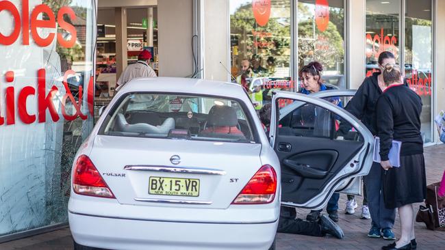 People assist an elderly driver who drove into the front door of Coles at Umina Beach. Picture: Gary Brown.