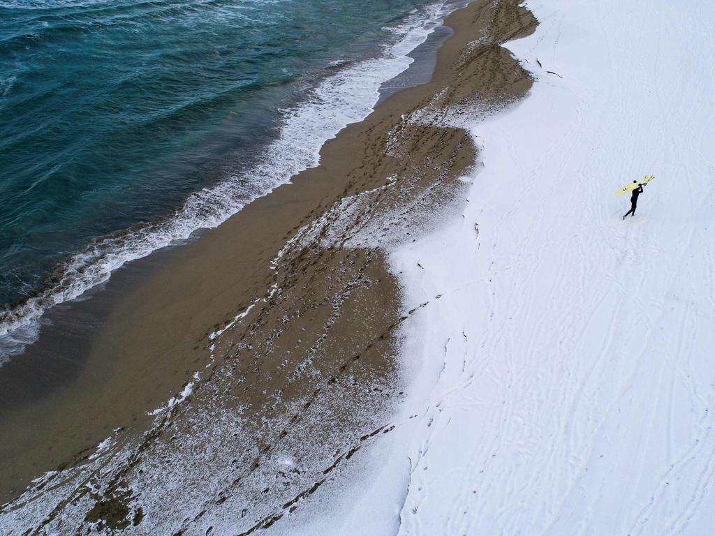 A surfer carries his surfboard as he walks through the snow out of the water on March 11, 2018 in Unstad, northern Norway, Lofoten islands, within the Arctic Circle as air temperature drops minus 13°C and water temperature above 4°C. Picture: AFP