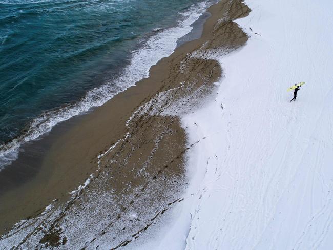 A surfer carries his surfboard as he walks through the snow out of the water on March 11, 2018 in Unstad, northern Norway, Lofoten islands, within the Arctic Circle as air temperature drops minus 13°C and water temperature above 4°C. Picture: AFP