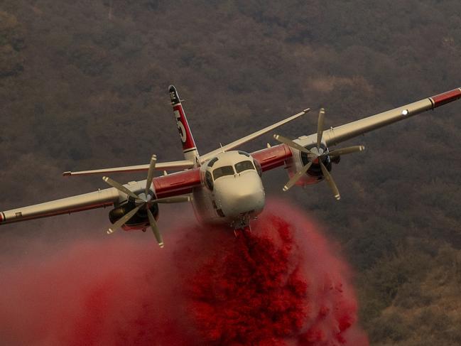 A Cal Fire S-2T firefighting tanker releases retardant while battling the Palisades Fire in the Mandeville Canyon neighborhood of Los Angeles, Calif., Saturday, Jan. 11, 2025. (Stephen Lam/San Francisco Chronicle via AP)