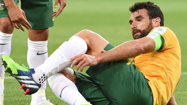 Australia's captain Mile Jedinak reaches for his injured ankle.