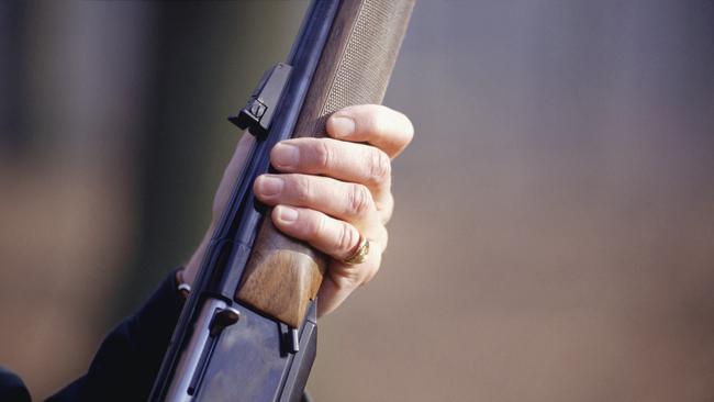 Man holding shotgun, mid section, close-up of hand. Gun. Rifle. Generic image.