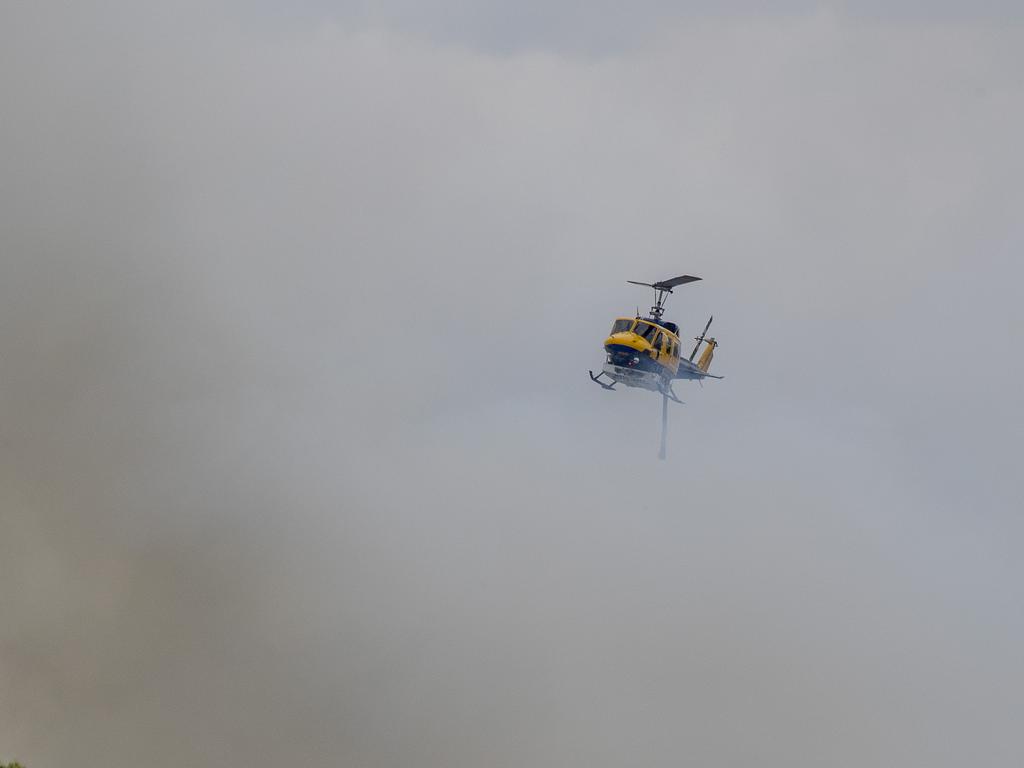 Smoke haze covers the Gold Coast Skyline from a grass fire at Carrara. A firefighting helicopter collects water from Judy Turners property in Carrara . Picture: Jerad Williams