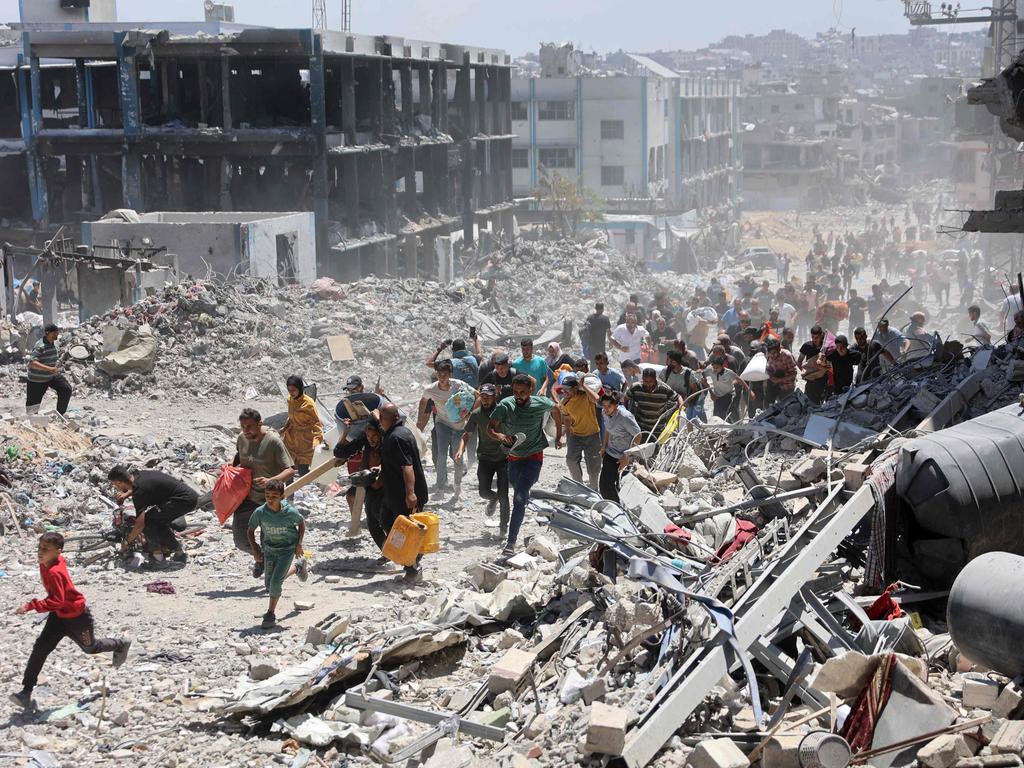 Palestinians who returned briefly to the Jabalia refugee camp in the northern Gaza Strip to check on their homes, run for cover after a school was hit by an Israeli strike. Picture: AFP