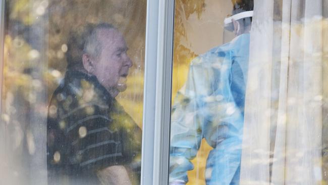 A heavily protected worker talks to a resident of the Arcare Aged Care at Maidstone, where a staff member has tested positive. Pictiure:Rob Leeson