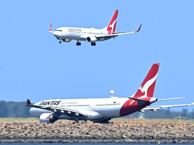 A Qantas plane (top) prepares to land at the Sydney International Airport on February 27, 2025. Australian airline Qantas said Thursday profits are up and demand for flights looks strong but it is still trying to win back trust after a string of scandals. (Photo by Saeed KHAN / AFP)