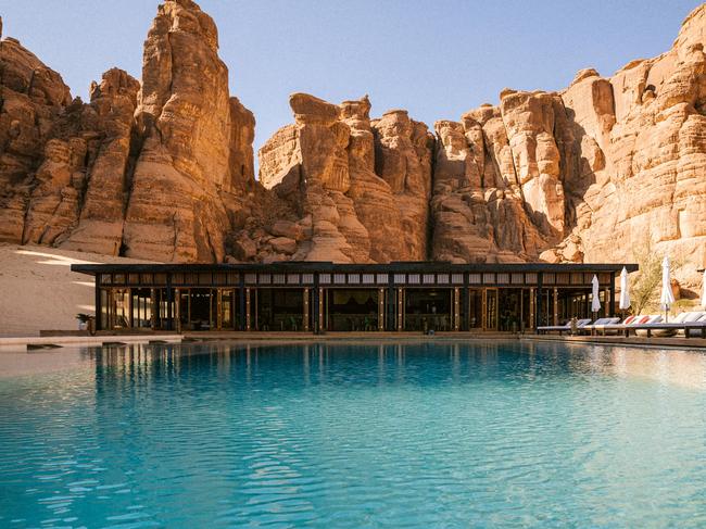 Travel & Luxury 16 December Issue 2022. Habitas.WORDS BY George Epaminondas. PR images supplied. The pool at Al-Ula in Saudi Arabia set against sandstone cliffs.