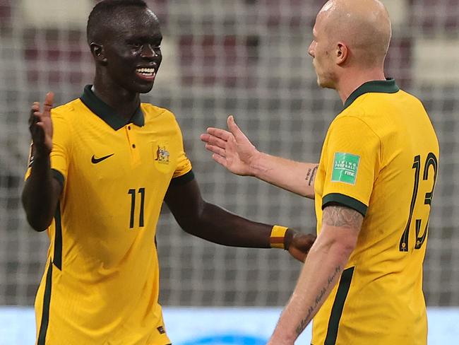 Australia's midfielder Aaron Mooy (R) and Australia's forward Awer Mabil celebrate their win in the 2022 Qatar World Cup Asian Qualifiers football match between Australia and Oman, at the Khalifa International Stadium in the Qatari capital of Doha, on October 7, 2021. (Photo by KARIM JAAFAR / AFP)