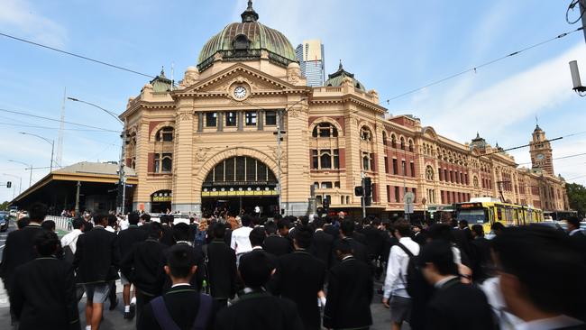 Pedestrians cross the road in front of Flinders Street Station in Melbourne, Thursday, March 21, 2019. Australia's unemployment rate fell 0.1 percentage points in February to a seasonally adjusted 4.9 per cent. (AAP Image/James Ross) NO ARCHIVING