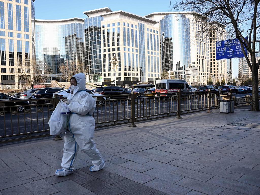 A woman wearing personal protective equipment walks along a street in Beijing. Picture: AFP