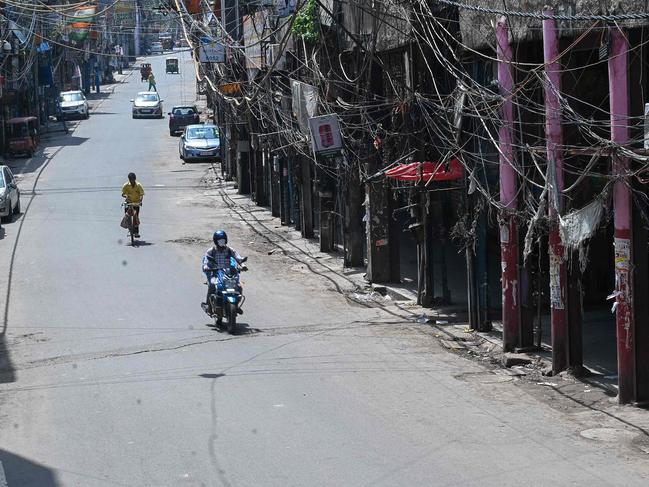 Motorists make their way through a partially deserted closed market in New Delhi, ahead of am easing of restrictions on Monday. Picture: Prakash Singh/AFP