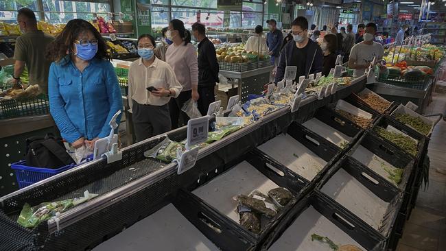 People shop for vegetables amid several empty shelves, in Beijing, China. Picture: Getty