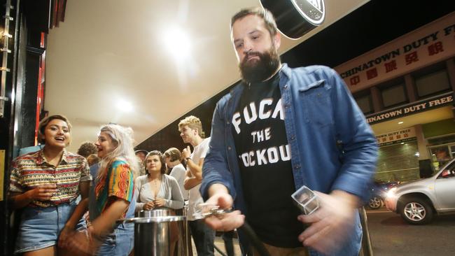 Outside The Foundry on Wickham St people wait to be ushered inside by a manager wearing a “F..k the lockout” T-shirt.