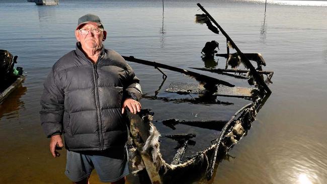 BURNT DREAMS: Errol Lindsay surveys the charred remains of his fishing boat at Lake Cootharaba. Picture: John McCutcheon