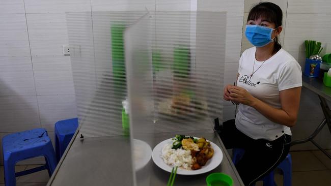 A woman eats lunch on a table fitted with a plastic partition at an eatery in Hanoi. Picture: AFP