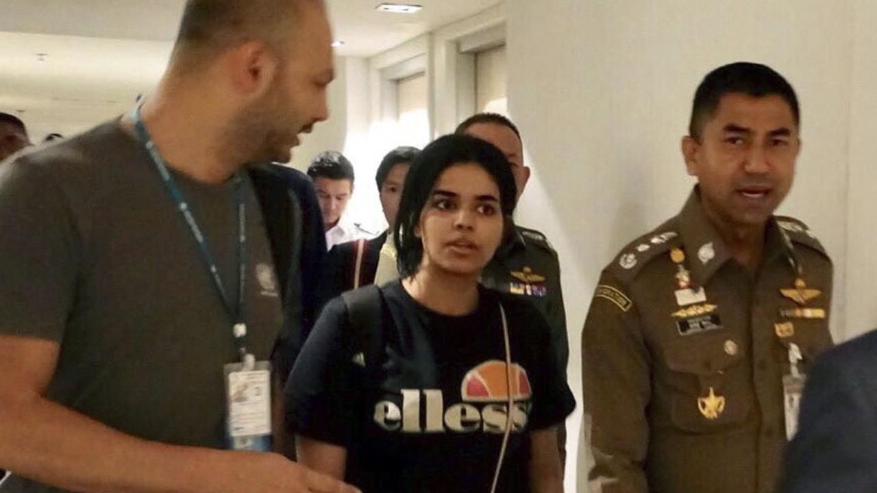 Chief of Immigration Police Maj. Gen. Surachate Hakparn, right, walks with Saudi woman Rahaf Mohammed Alqunun before leaving Suvarnabhumi airport in Bangkok. Picture: AP