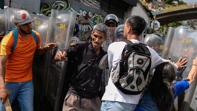 People confront riot police during a protest against the shortage of food, in Caracas on December 28. President Nicolas Maduro attributes the shortage to “international sabotage”. Picture: AFP/Federico Parra