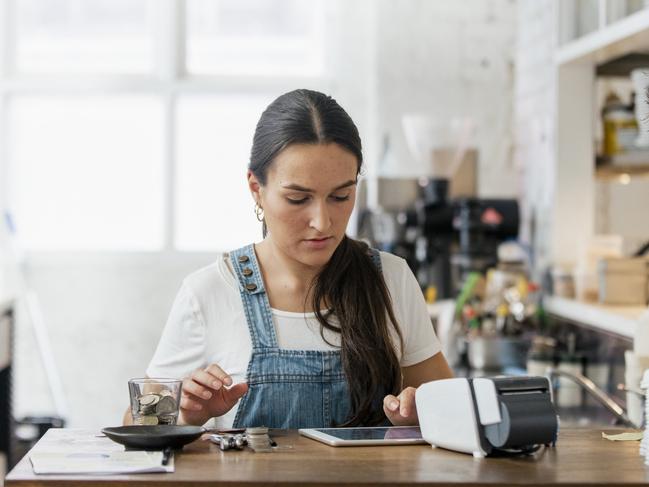 A front view shot of a waitress handling money behind a counter in a cafe.