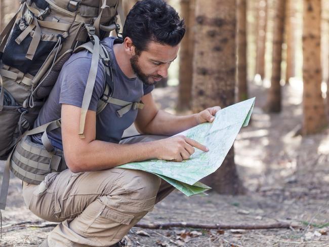 Beard Man with Backpack and map searching directions in wilderness area