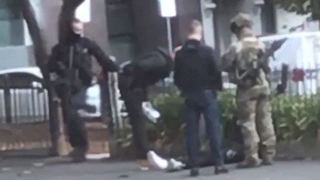 Heavily armed officers detain a man on the ground outside a church in North Melbourne. 