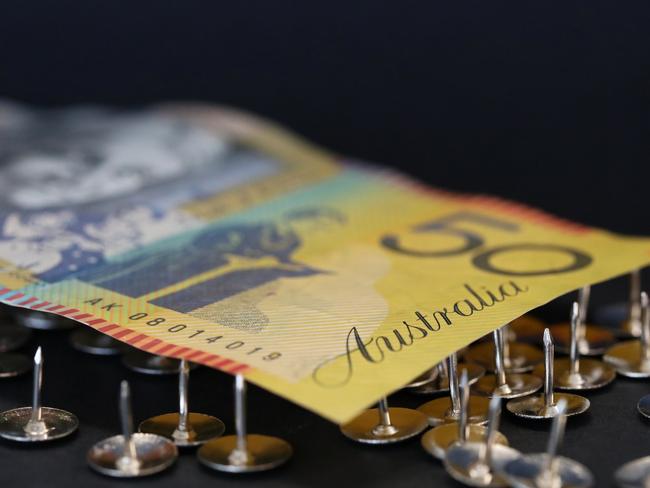 close up extreme shallow depth of field macro shot of australian fifty dollar note supported on sharp thumb tacks or drawing pins. Finance business economy concept. Debt trap generic money