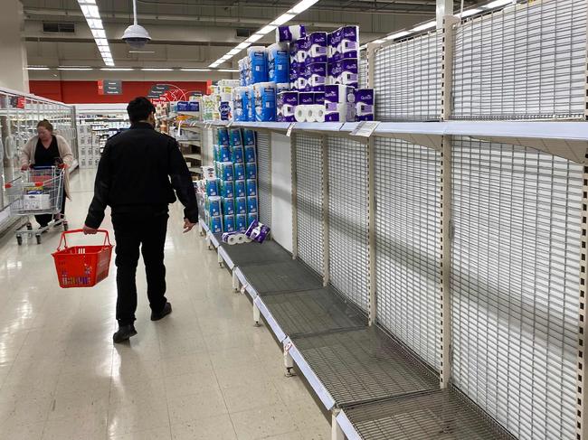 A shopper walks past near-empty shelves of toilet paper at a supermarket in a Melbourne on June 26, 2020. - Supermarkets imposed purchase limits on toilet paper across Australia on June 26 following panic buying by people rattled over a surge in coronavirus cases in the country's second-biggest city. (Photo by William WEST / AFP)