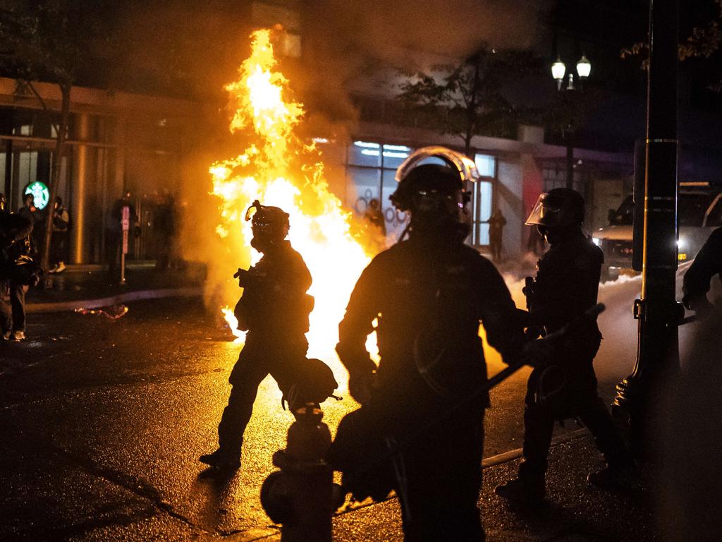 Police walk past a fire started by a Molotov cocktail in Portland, United States. Picture: Nathan Howard/Getty Images/AFP