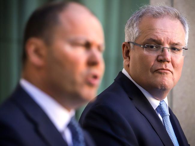 Australian Prime Minister Scott Morrison (R) reacts as he stands with the Australian Treasurer Josh Frydenberg during a press conference at Australia's Parliament House in Canberra on March 22, 2020. - Morrison told citizens to cancel any domestic travel plans to slow the spread of coronavirus, warning stronger measures were imminent to deal with localised outbreaks. (Photo by DAVID GRAY / AFP)