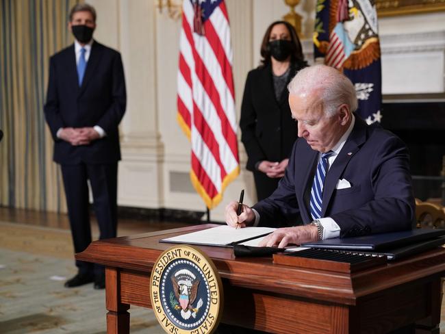 US Vice President Kamala Harris (2-L) and Special Presidential Envoy for Climate John Kerry (L) watch as US President Joe Biden signs executive orders after speaking on tackling climate change, creating jobs, and restoring scientific integrity in the State Dining Room of the White House in Washington, DC on January 27, 2021. (Photo by MANDEL NGAN / AFP)