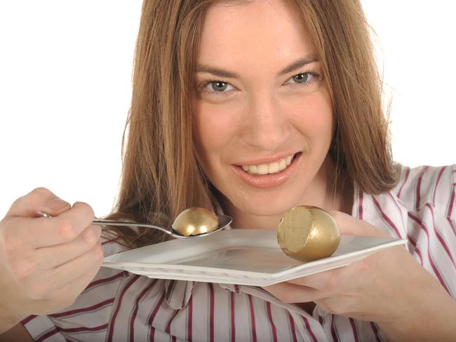 Your Money superannuation generic images. Woman eating golden nest egg with spoon from plate.