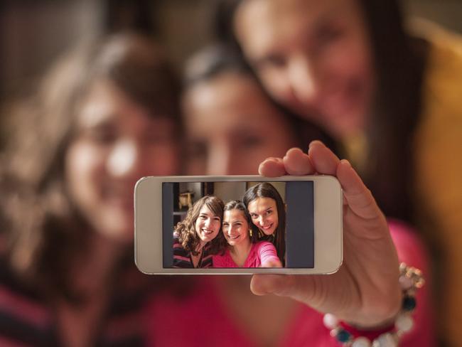 iStock. 3 girls with a smartphone performing a selfie. For Bill Rule. Budget Busters.