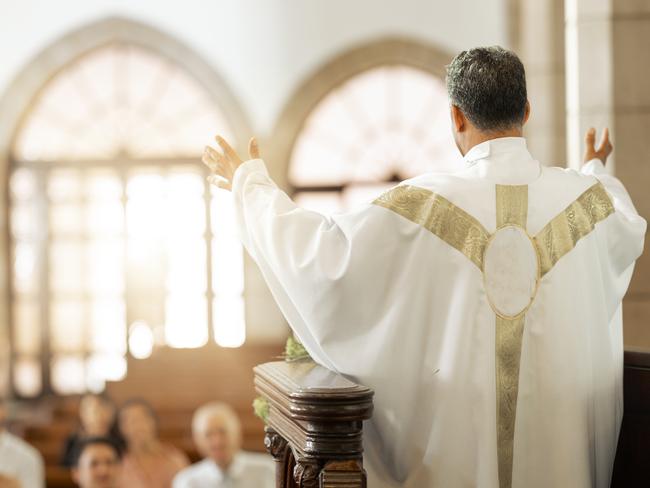 Pastor, church and man praying for his congregation to god for spiritual wellness on a Sunday. Hope, religious and priest preaching to christian people standing on a podium in a cathedral building.