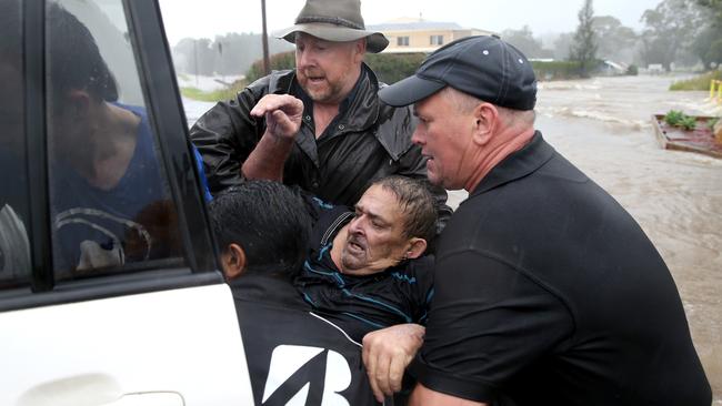 A man is rescued by local residents after the found him clinging to a tree in raging floodwaters at Telegraph Point on the state’s north. Picture: Nathan Edwards