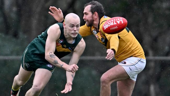 Old Eltham Collegians’ Bradley Johnstone handballs under pressure. Picture: Andy Brownbill