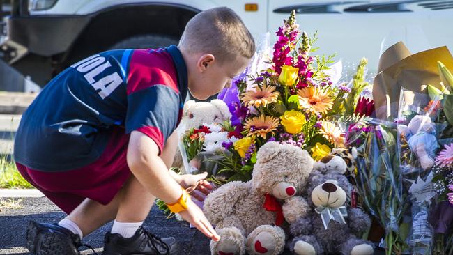 A child pays tribute at the scene of the crash in Alexandra Hills where Matty Field and Kate Leadbetter were killed by an out of control stolen car while walking their dog. Picture: Nigel Hallett