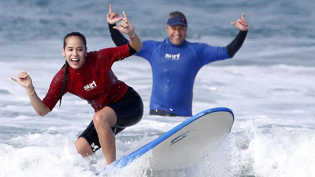 Surf teacher, Chris Maley from Learn to Surf in Paradise with client Shae-Yvonne De La Cruz, 18, from Brisbane, learning to surf at the Spit. For a story about potential funding cuts to tourism. Picture: JERAD WILLIAMS