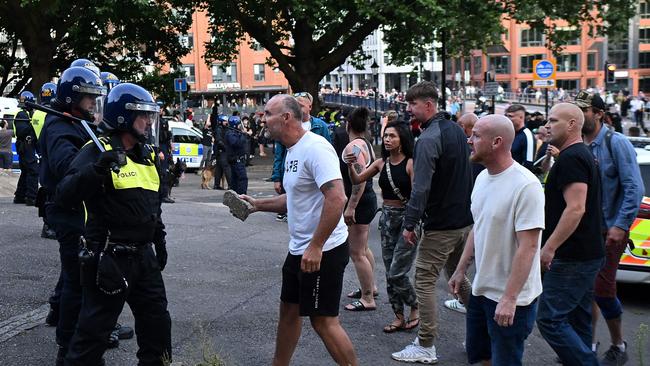 A protester holding a piece of concrete walks towards riot police as clashes erupt in Bristol this month. Picture: AFP