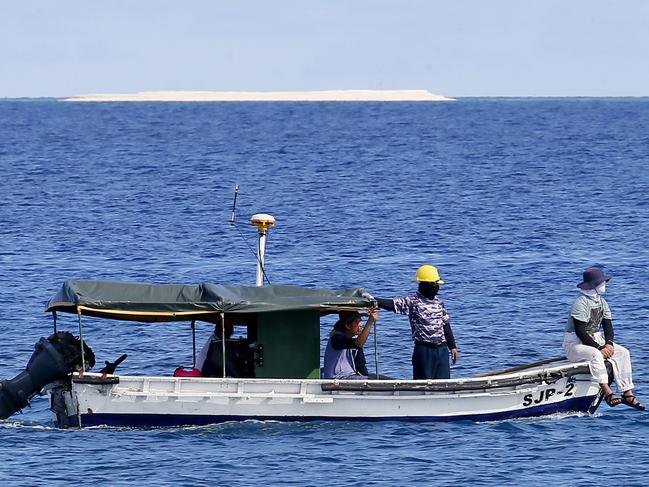 Philippine Government engineers survey the area around the Philippine-claimed Thitu Island with a sandbar sitting on the horizon off the disputed South China Sea. Picture: AP