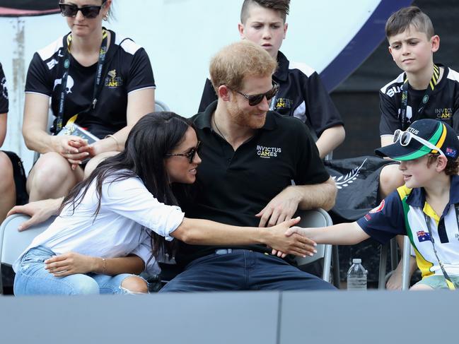 Prince Harry and Meghan Markle talk with a child while attending a Wheelchair Tennis match during the Invictus Games 2017 at Nathan Philips Square on September 25, 2017 in Toronto, Canada. Meghan can be seen here trying to shake the hand of Bailey Lawler (R), son of Sean Lawler who was competing. Picture: Getty Images